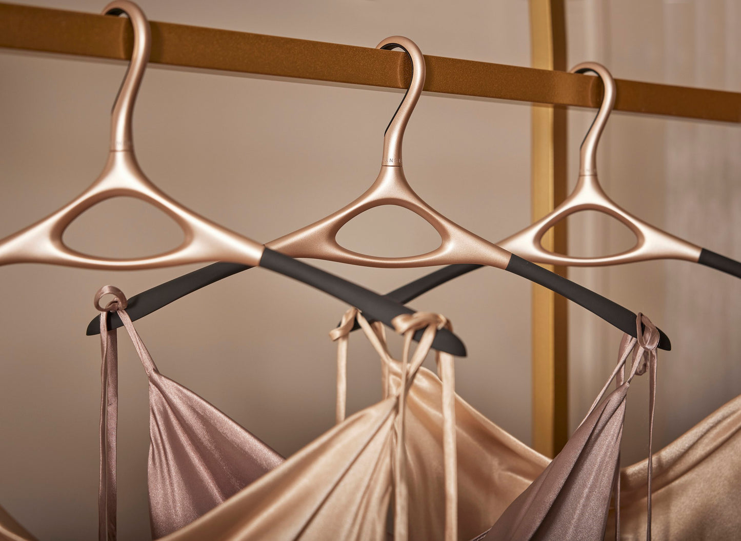 Image of Lou Hansell's L series base wedding dress hangers in Yellow Gold gold lined up on a rail and holding different gowns.