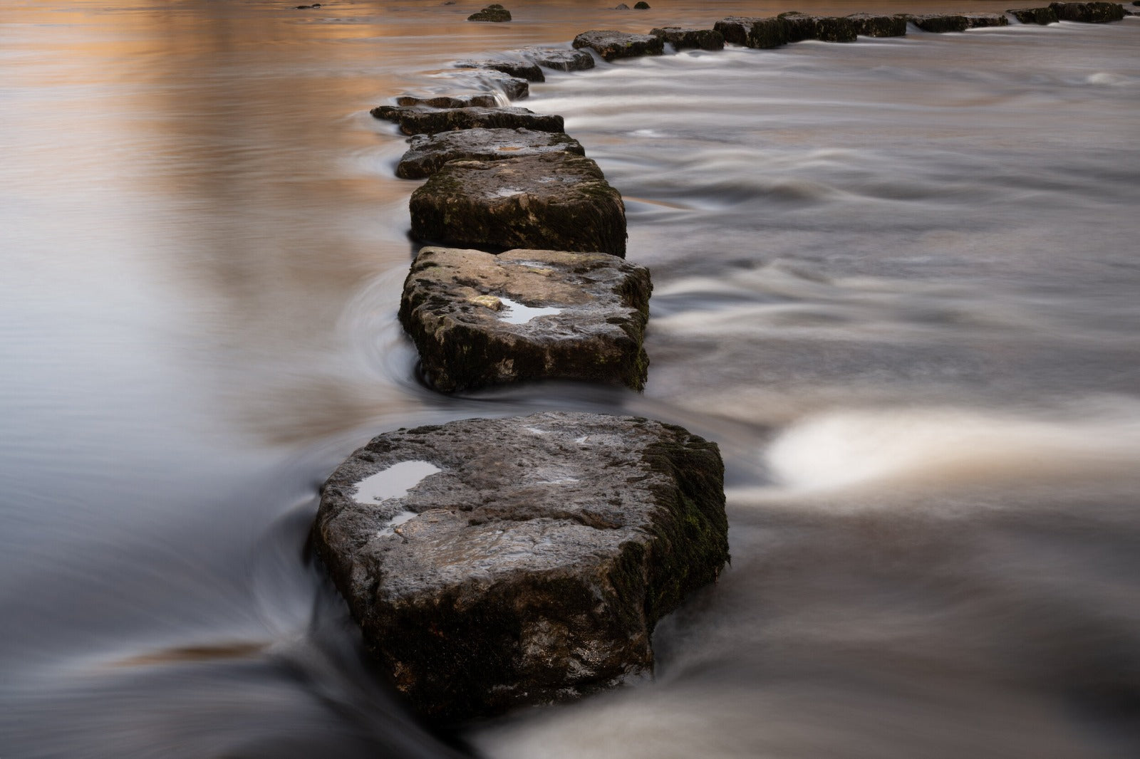 Water flowing smoothly over stones, symbolizing the harmony and sustainability at the heart of Lou Hansell craftsmanship.