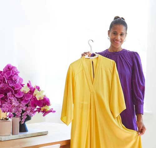 Isolde Brielmaier holding a vibrant yellow dress on a Lou Hansell clothes hanger, celebrating craftsmanship and luxury design.