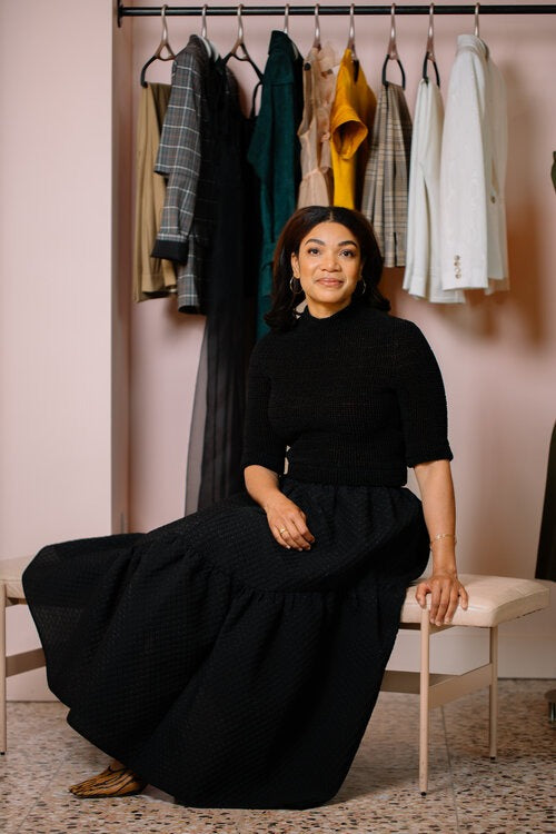 Sherry McMullen, McMullen Boutiques, sitting in front of clothes on Lou Hansell hangers