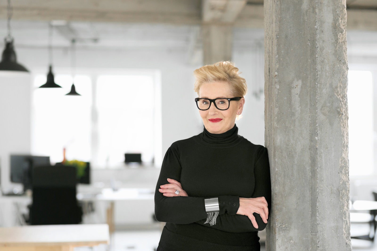 A woman leaning against a column in an office