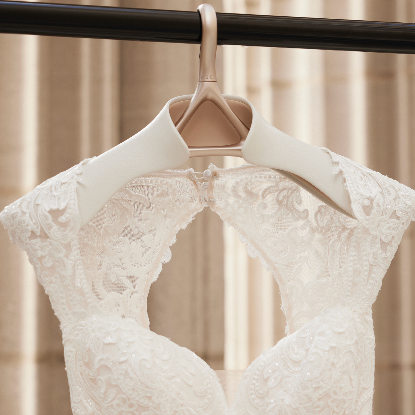 A front view of a wedding dress hanging on a Lou Hansell bridal hanger.