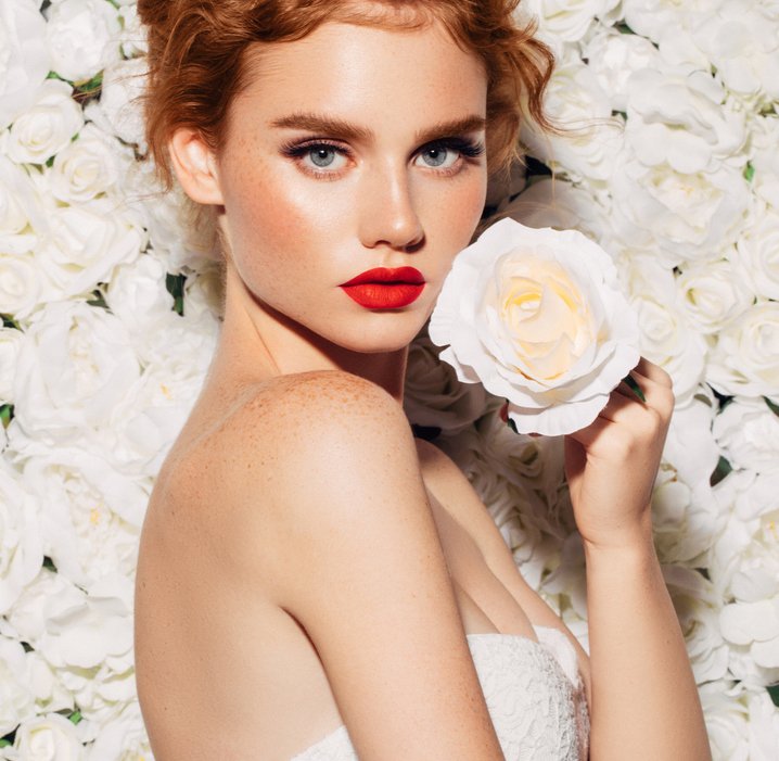 Woman in a white dress with white roses as a background 