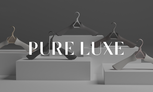 Image that says pure luxe with hangers on pedestals in background. 